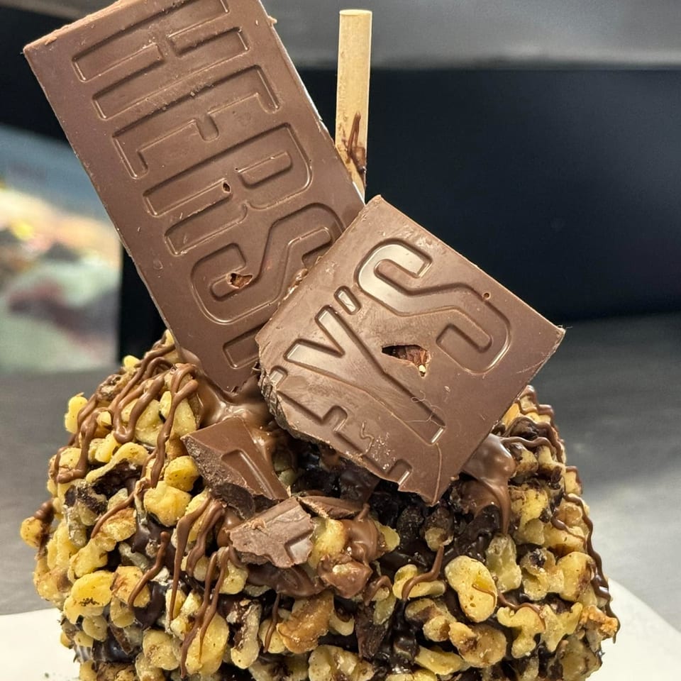 A donut from The Donut Factory, covered in nuts, chocolate drizzle, and Hershey's chocolate bars.