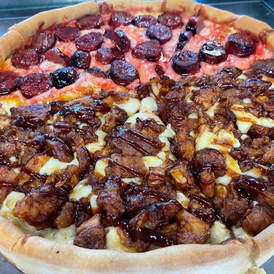 A close-up of a half-pepperoni, half-BBQ chicken pizza with a thick crust.
